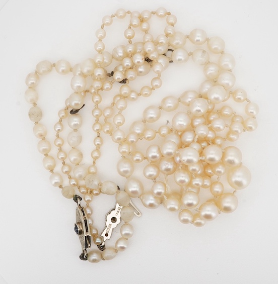 Two single strand cultured pearl necklaces, one graduated with 18ct, plat and three stone diamond set clasp, 60cm, the other with cabochon sapphire set unmarked clasp (a.f.). Condition - poor to fair.